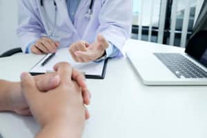 Doctor and patient close up of hands on desk